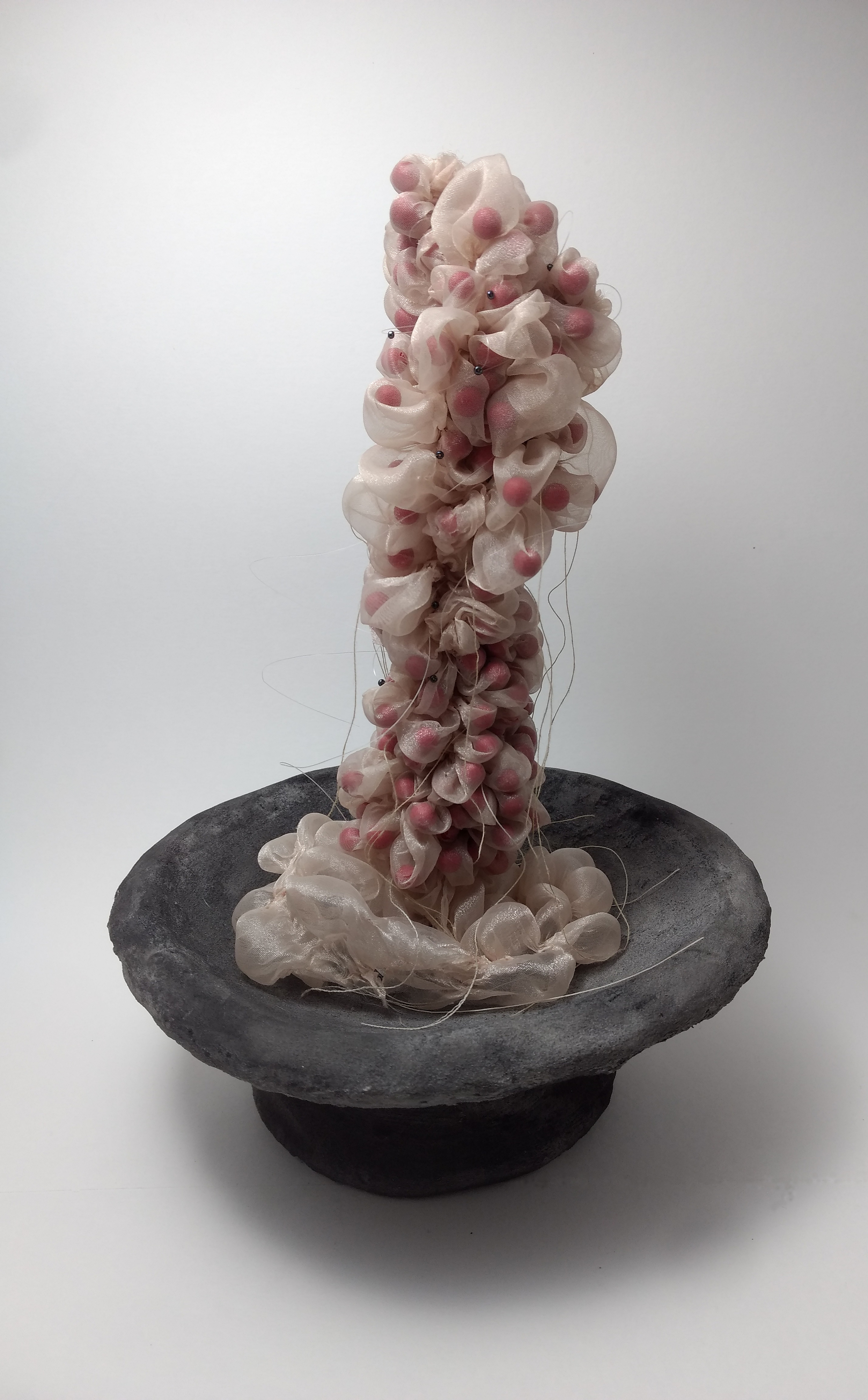 Art: sculpture featuring fabric stretched over red "eye"-type balls, growing out of a grey bowl
